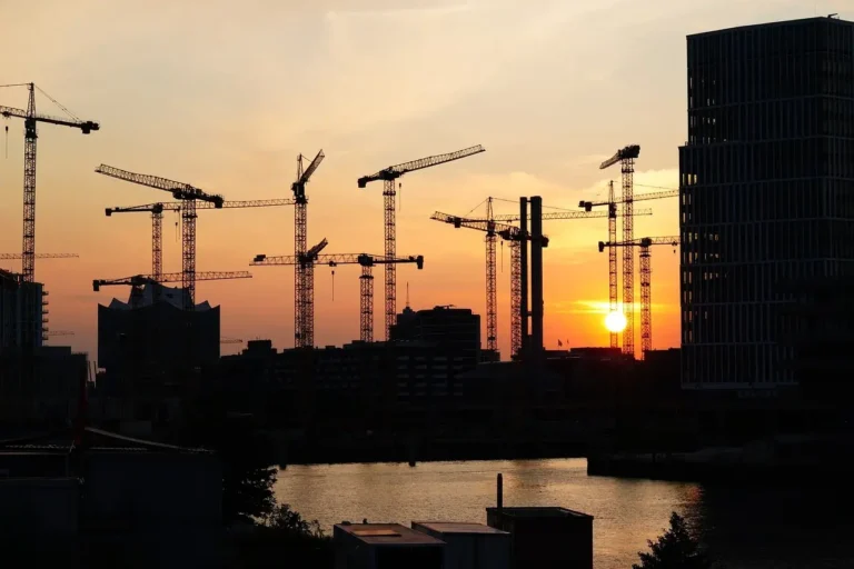 Grues à tour sur un chantier au coucher du soleil, illustration de la formation R487 avec évaluation ACES à Lyon.